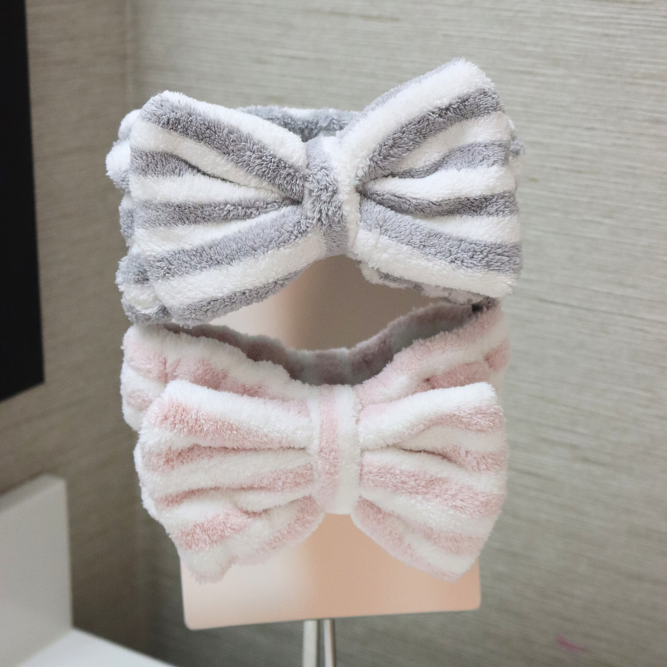 Gray-and-white and pink-and-white striped bow spa headbands on a display stand