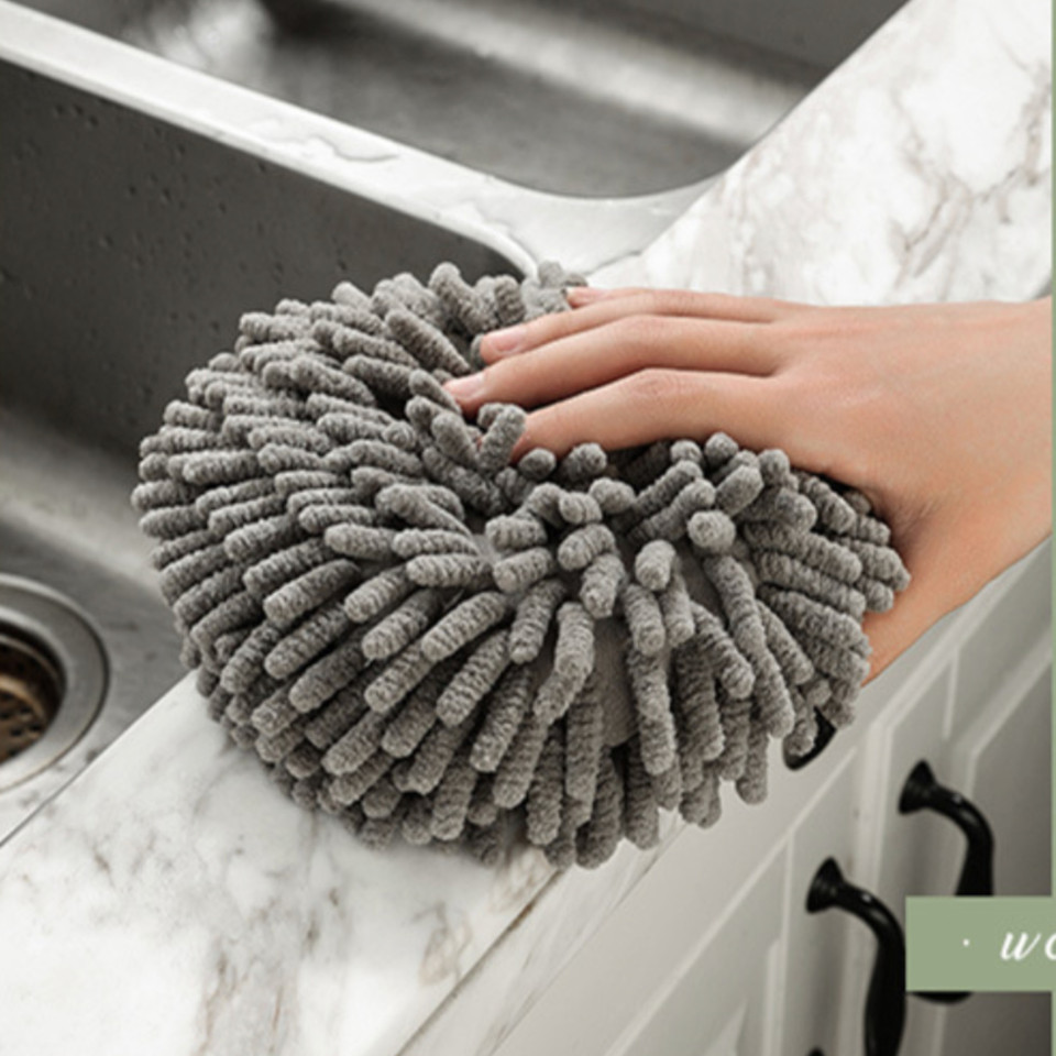 Hand resting on a gray round hand towel beside a sink