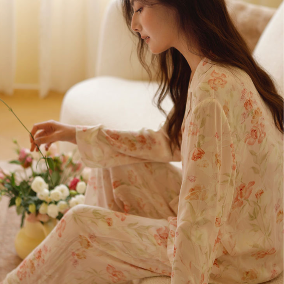 Side view of the Pink Still Bloom floral pajama set in a seated lounge setting