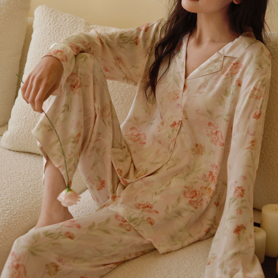 Woman seated in the Pink Still Bloom floral pajama set, showing the relaxed top and pants