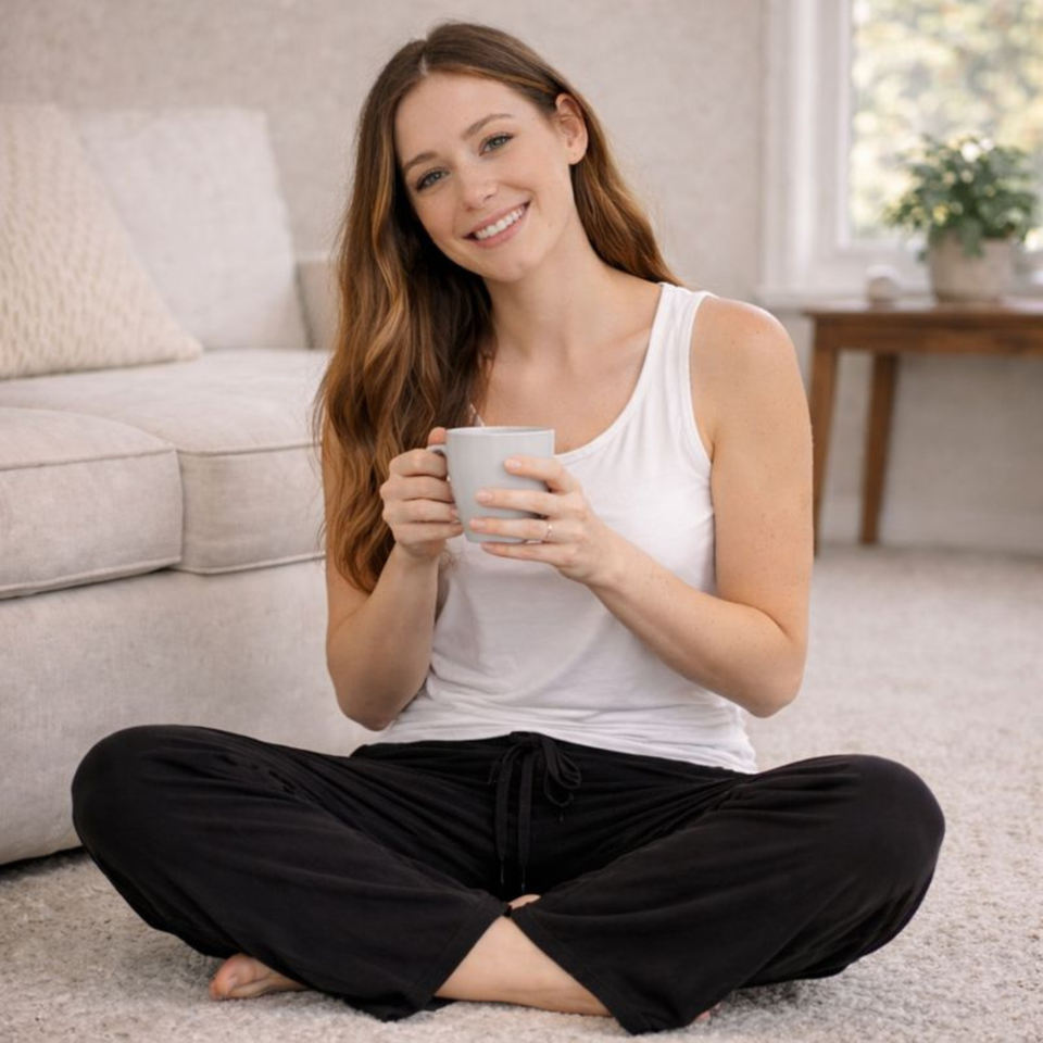 Woman relaxing in white built in bra tank and black lounge pants