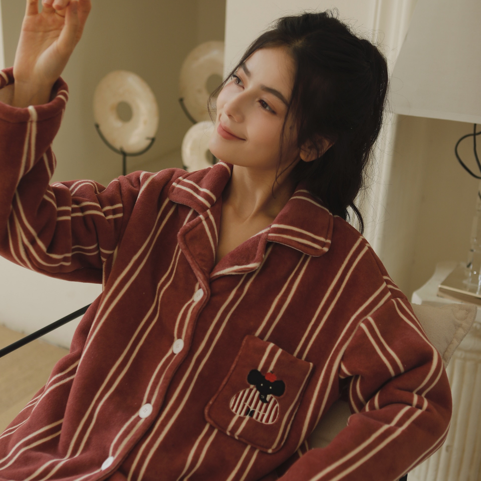 Close-up of rust red striped pajama top with notched collar, buttons, and embroidered pocket
