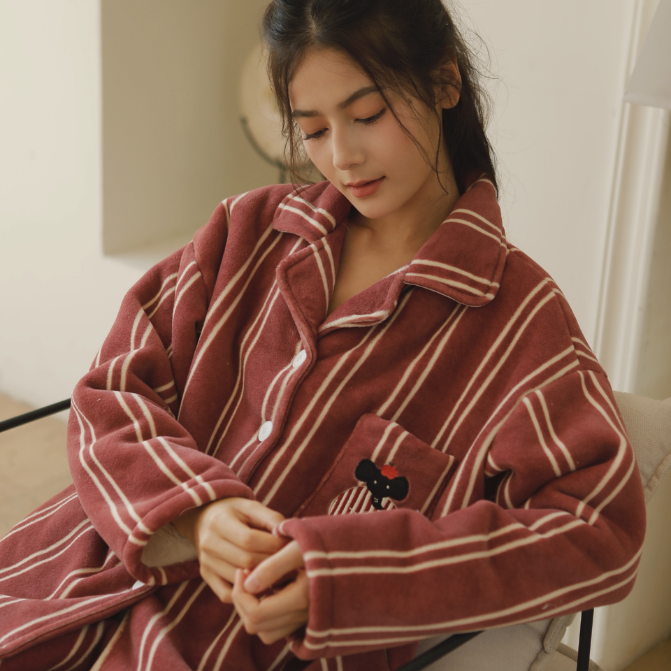 Woman seated in a relaxed rust red striped fleece pajama top with long sleeves