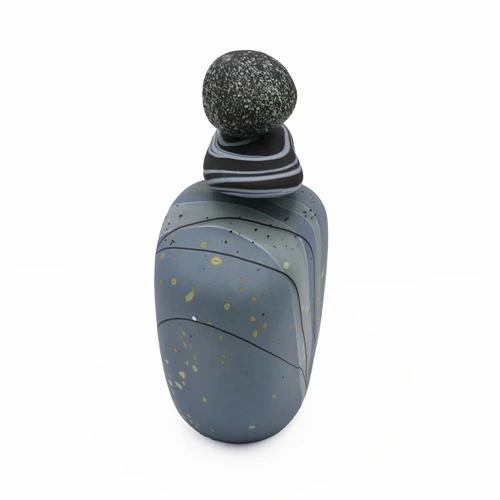 Side view of blown glass cairn sculpture by Melanie Leppla with three glass stones stacked on top of a blue-gray base