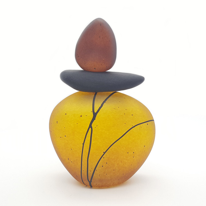 Blown glass cairn sculpture by Melanie Leppla with two glass stones stacked on top of a golden yellow base