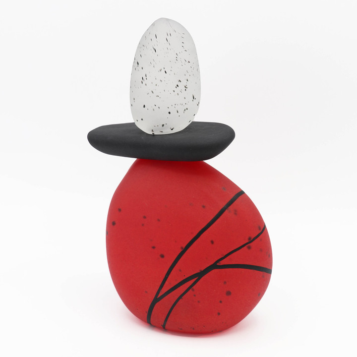 Blown glass cairn sculpture by Melanie Leppla with two glass stones stacked on top of a red base