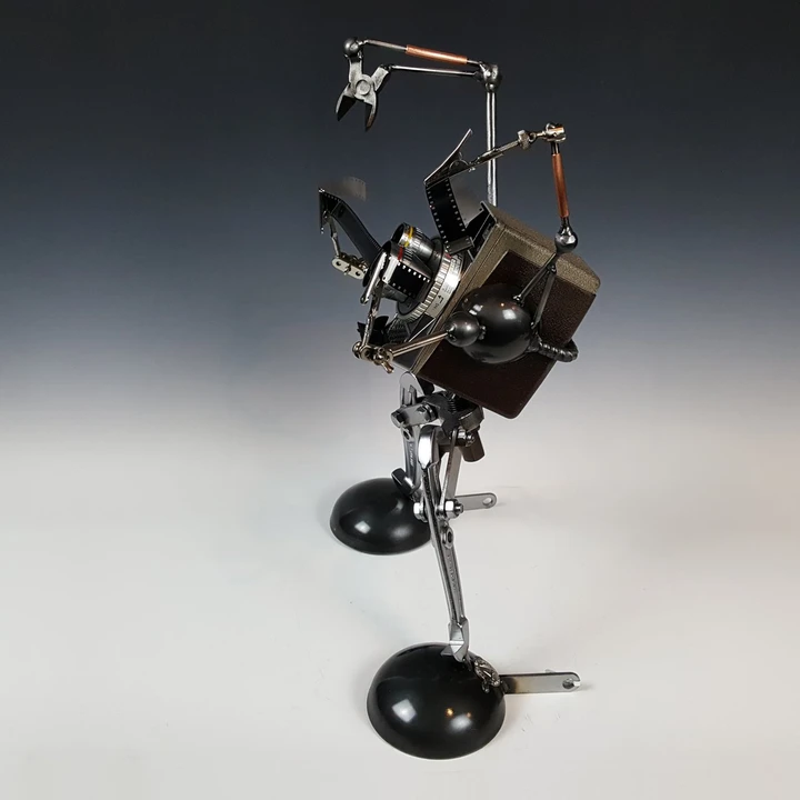 Director's Cut - DeJUR Electra Movie Camera robot sculpture holding film strips, vintage camera and steel by Adam Homan