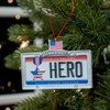 Ornament License plate with sentiment reading “Honor All Who Serve Hero Duty Honor Courage” and American flag and star medal with flag motif