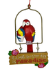 This Christmas ornament features a red, yellow, and blue macaw parrot holding a matching snow cone while perched above a hanging sign that says "It's Just Another Day In Paradise" with flowers