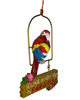 This Christmas ornament features a red, yellow, and blue macaw parrot holding a matching snowcone while perched above a hanging sign that says "It's Just Another Day In Paradise" with flowers