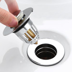 A sleek, stainless steel floor drain filter featuring a smooth surface with a central, spring-loaded Bounce CORE mechanism designed to prevent water backflow and blockages. A sleek, stainless steel floor drain filter featuring a smooth surface with a central, spring-loaded Bounce CORE mechanism designed to prevent water backflow and blockages.
