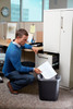 FG295600BLA - An office worker is knelt at a filing cabinet and can be seen disposing of documents into the wastebasket