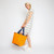 woman holding orange nylon tote bag with navy straps