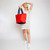 woman holding red nylon tote bag with navy straps