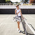 Woman stands on pickleball court next to the net holding a canvas pickleball tote with navy trim. Bag has navy stripes and the initials "LRA" painted on the front of the tote.