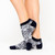 woman wears a pair of grey socks with navy and grey snakeskin and white tennis racquets pattern