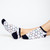 woman wears white socks with pattern of navy crossed golf clubs and rainbow hearts