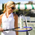 Women holds tennis racquet with white water bottle on top of racquets.White water bottle with repeating green tennis balls and navy love text pattern on the bottle. 