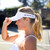 woman on a tennis court wearing a white visor with navy rainbow crossed paddle pattern repeat