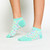 girl wearing pair of light green kids socks with pastel rainbow tennis balls stitched around socks