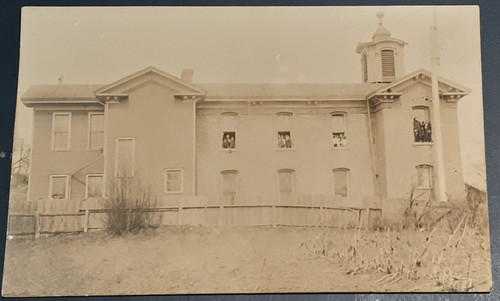 People leaning out windows and standing on window ledge of building