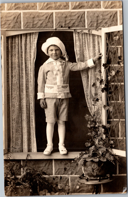 RPPC Boy in spring easter suit and hat standing in window on ledge AZO 1904-18