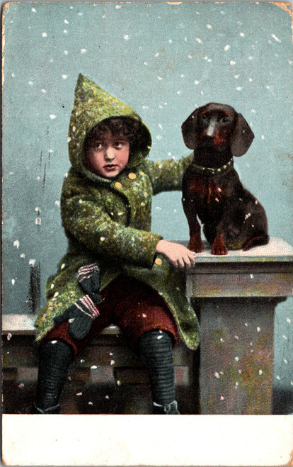 Boy in Green Coat sitting with dachsund in snow