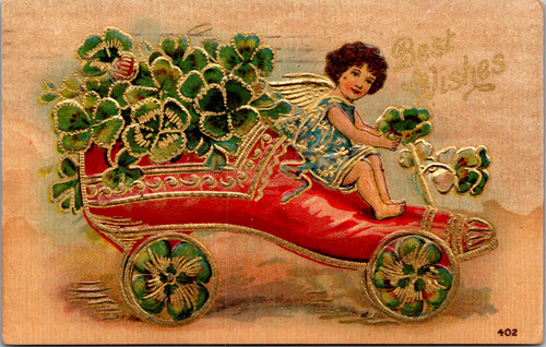 Best Wishes cherubic child driving red shoe shaped car filled with green clovers