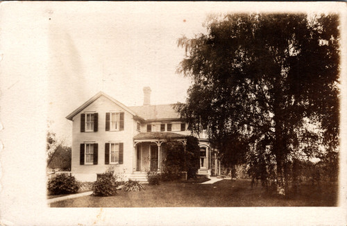 Two story victorian home with large tree