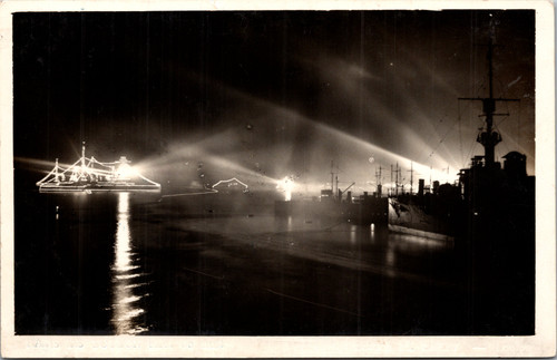 Vintage RPPC showing illuminated warships and harbor lights at night Toulon France titled Rade de Toulon Effet de Nuit