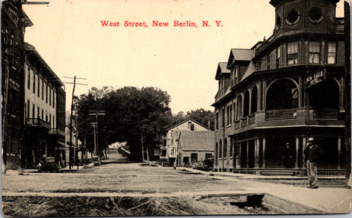 West Street in New Berlin New York showing the New Eagle Hotel, storefronts, dirt road, and horse and wagon era street scene.