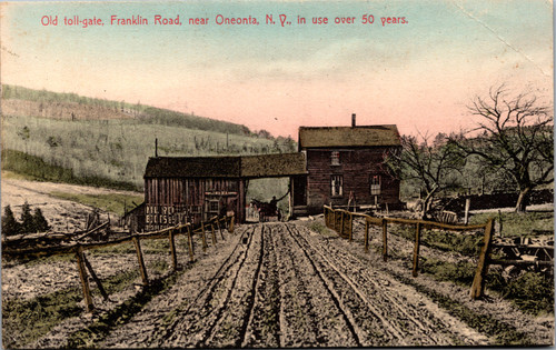 Color-tinted postcard showing a dirt road leading to a wooden toll-gate on Franklin Road near Oneonta, New York, with a horse and carriage passing underneath and fenced countryside around it.