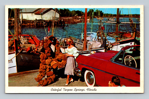 A beautiful woman next to a red Lincoln Capri negotiates with a man selling sponges