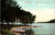Tinted postcard showing Five Mile Point on Otsego Lake in Cooperstown New York with shoreline trees and boats.
