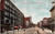 Tinted postcard showing Genesee Street looking south in Utica New York with trolley autos pedestrians and multi story commercial buildings