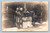 real photo postcard of women and a man sitting on porch steps