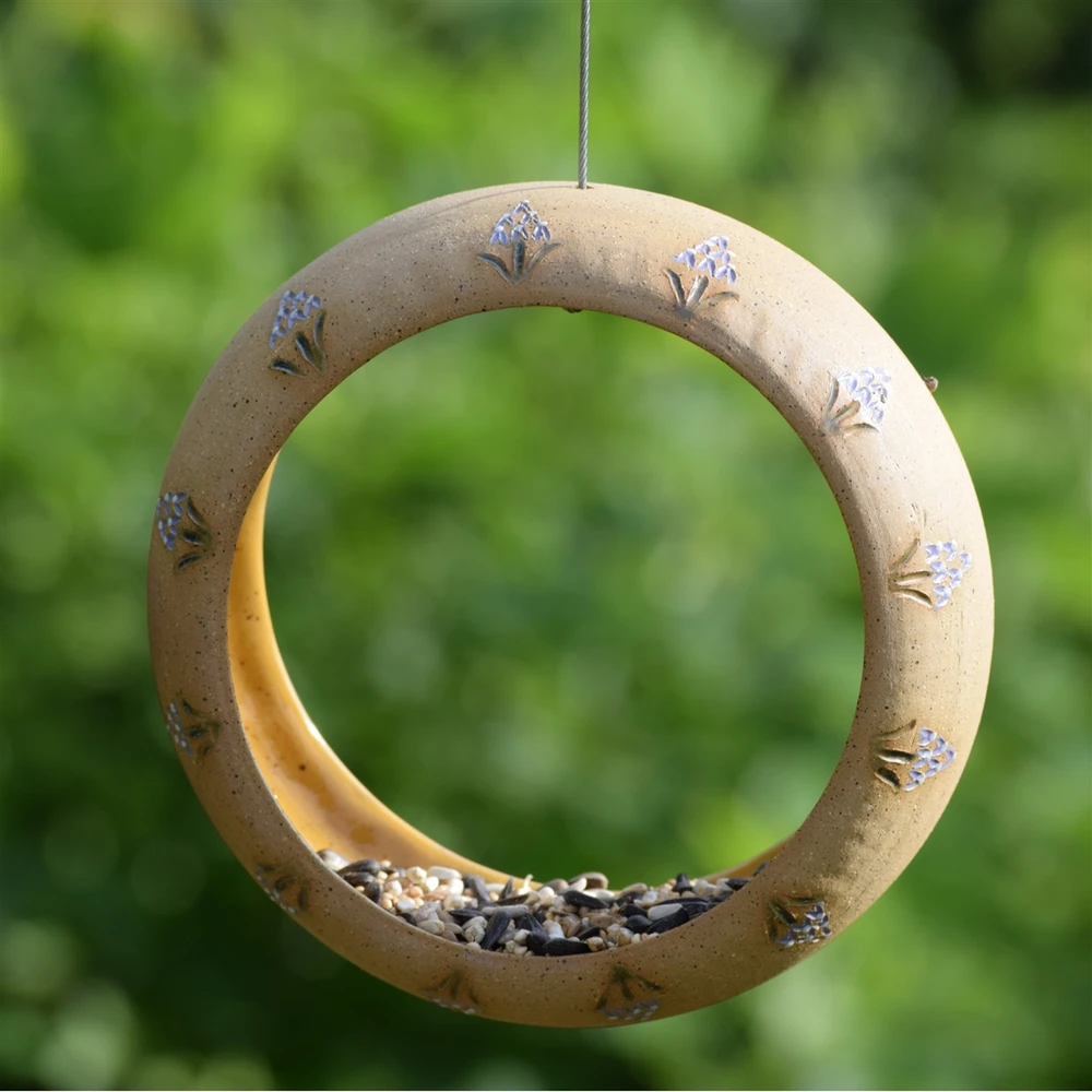 Handmade Alabama ceramic fly-through bird feeder hanging outdoors with birds feeding