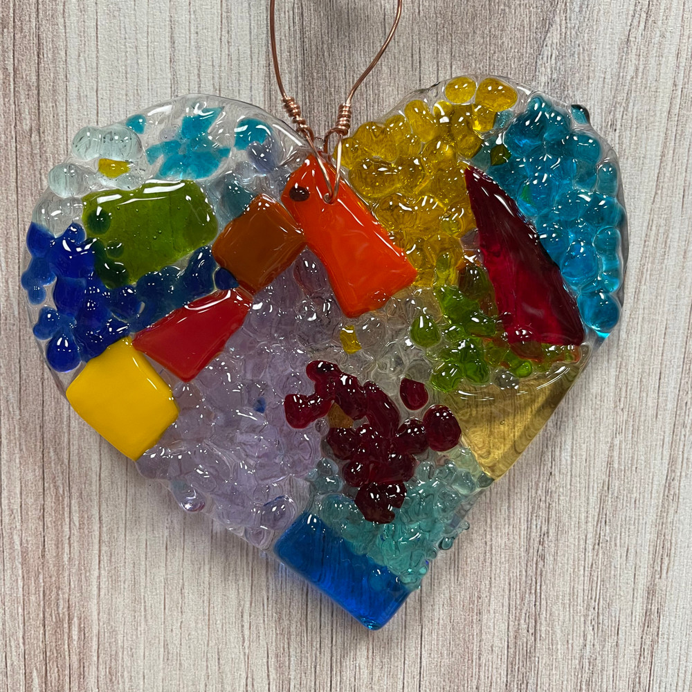 Sunlit fused glass heart ornament suncatcher hanging in window, handcrafted lemon yellow glass heart decor, Alabama artisan gift