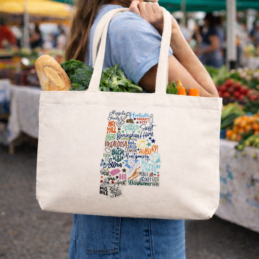 Centered on the tote is a colorful graphic shaped like the state of Alabama. The design is composed of:Hand-lettered city names and phrases