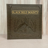 Black Belt Bounty deluxe cowhide coffee table book featuring Alabama hunting, fishing, wildlife photography, Southern recipes, and outdoor traditions.