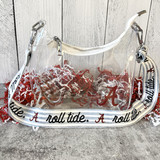 A clear University of Alabama gameday bag with white trim, gold hardware, and adjustable printed strap featuring Crimson Tide icons including Big Al and Roll Tide