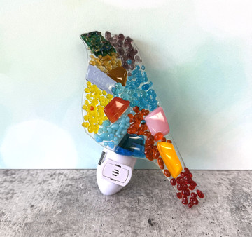 Fused glass bird night light glowing softly in a bedroom setting
633-00033