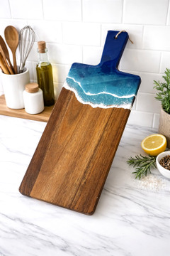 Handcrafted ocean resin cutting board with turquoise coastal wave design on natural wood, Alabama-made serving and charcuterie board with handle