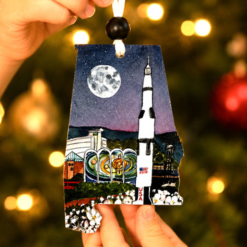 Alabama-shaped Christmas ornament featuring the U.S. Space & Rocket Center and Saturn V rocket in Huntsville, Alabama under a moonlit sky