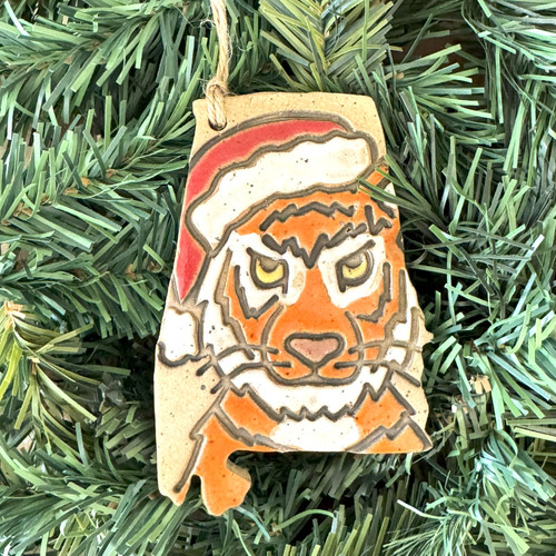 Hand-painted Alabama-shaped Christmas ornament featuring a festive tiger wearing a Santa hat, handmade in Alabama for unique Southern holiday décor.