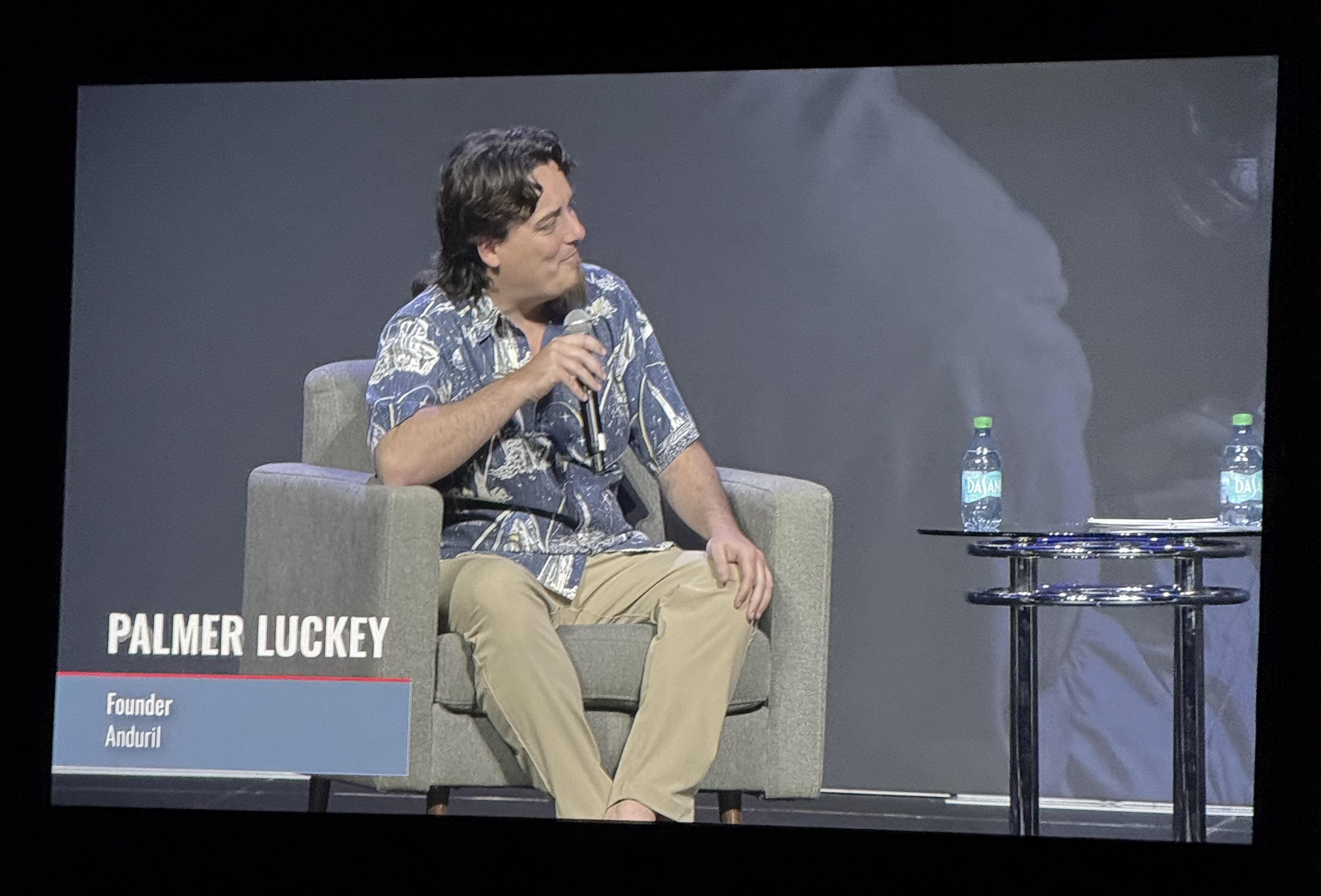 Palmer Luckey, founder of Anduril, speaking on screen during the day-one keynote conversation with the Hon. Michael Cadenazzi at DIBX 2026, the Defense Industrial Base Accelerator in Philadelphia