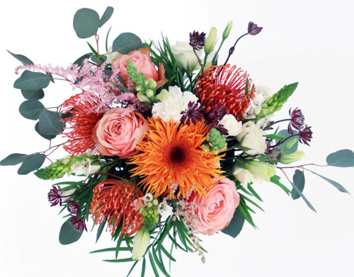 Loosely arranged bouquet in shades of coral & pink with eucalyptus accents to create a freestyle look.