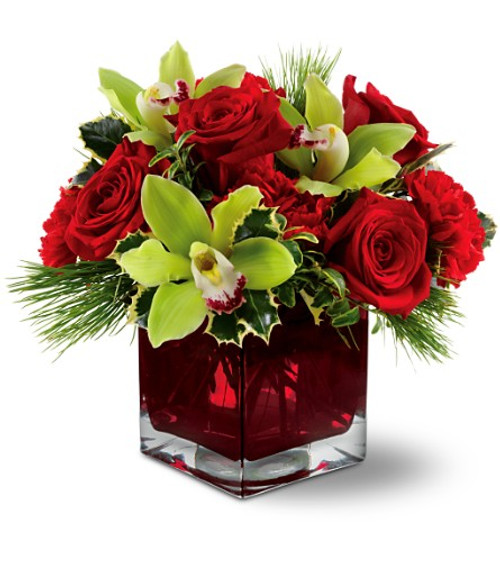 Green cymbidium orchids, red roses and carnations accented with holly and fresh pine in a red cube vase. Green cymbidium orchids, red roses and carnations accented with holly and fresh pine in a red cube vase.