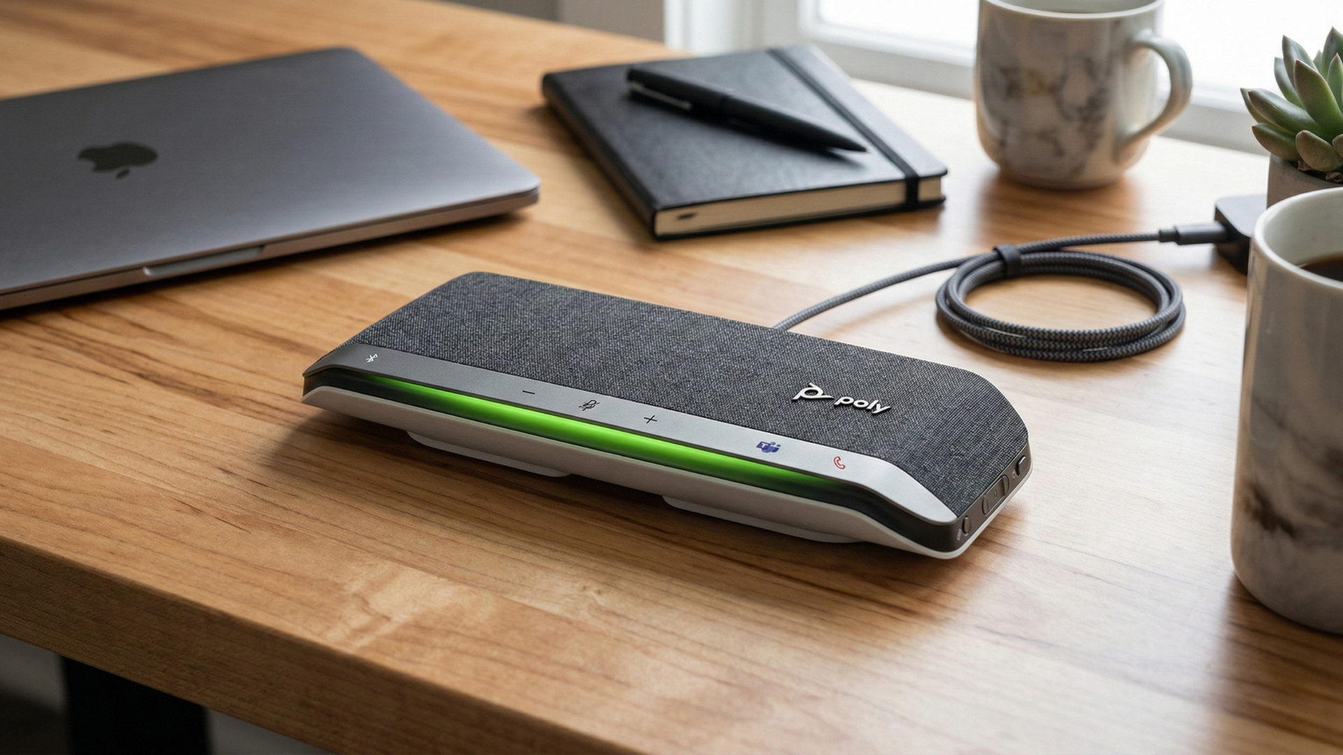 A detailed photograph of the Poly Sync 40+ Bluetooth Speakerphone on a richly grained maple wood desk.