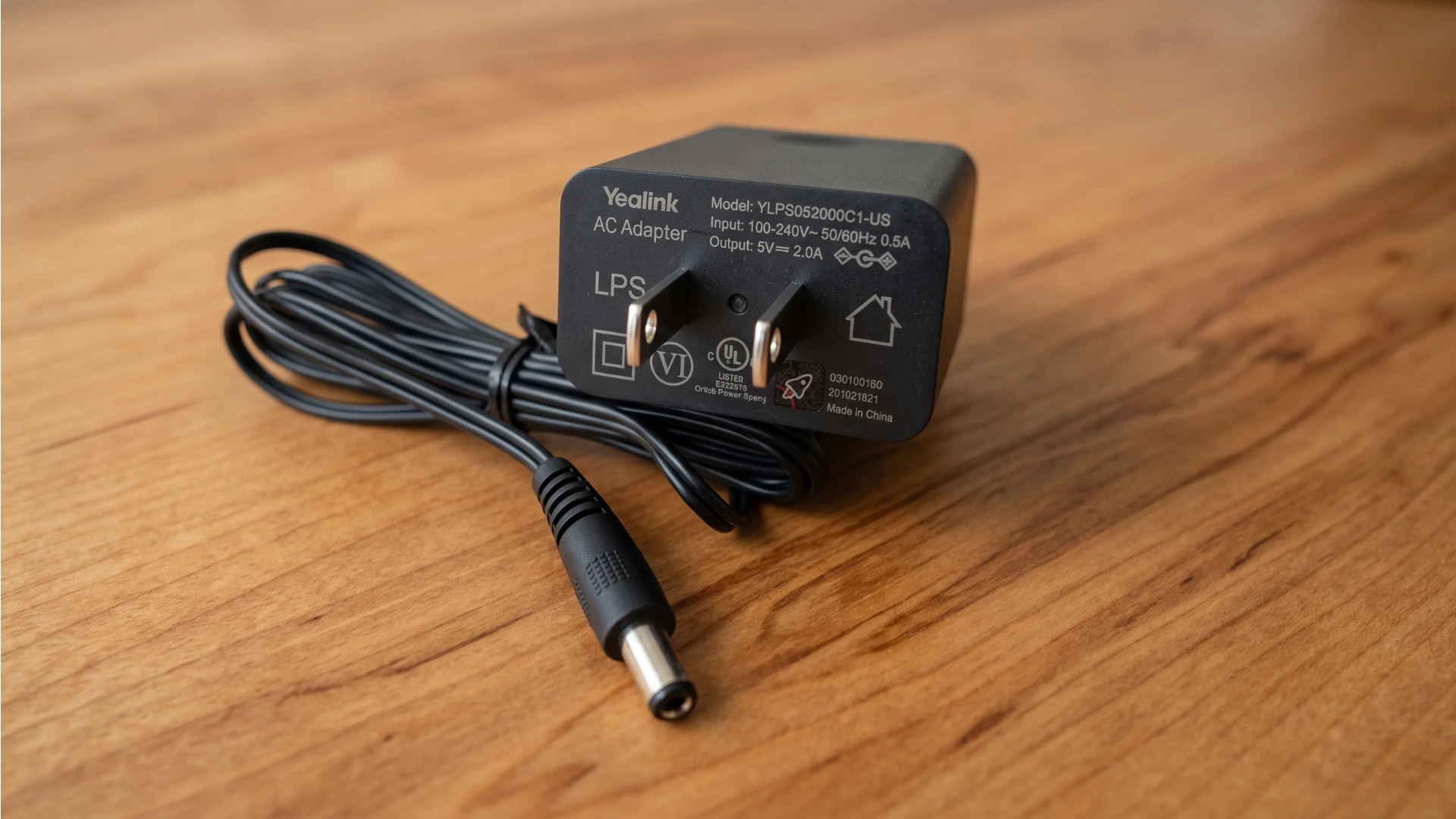 The Yealink PS5V2000US power adapter, a black US wall-plug power supply rated 5V DC at 2A, with its attached barrel connector cable.